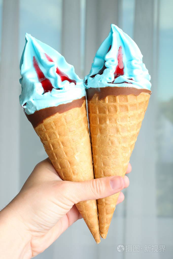 两个蓝色冰淇淋手上有果酱窗户背景