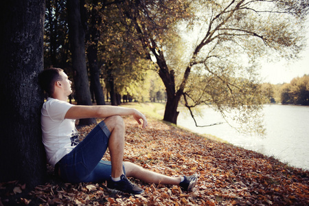 年轻人坐在秋天的公园