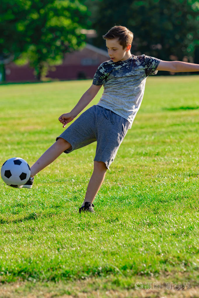 少年前男孩在公园踢足球