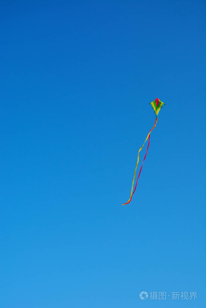 彩虹条纹风筝在晴朗的天在蓝天上飞翔.