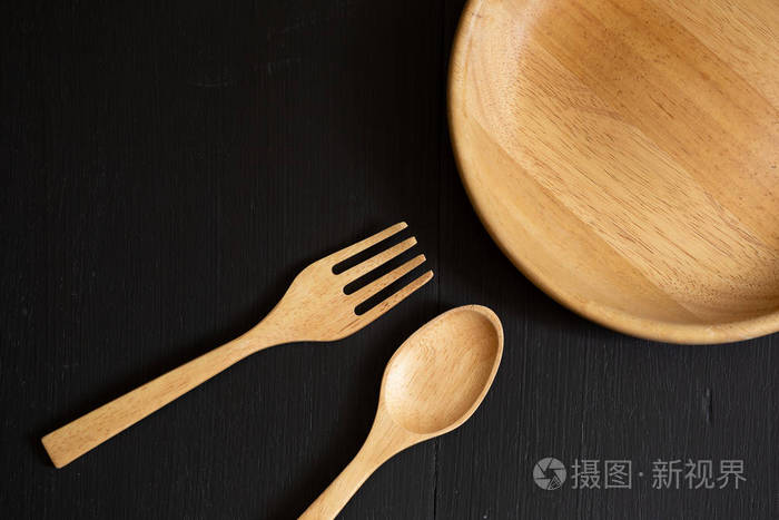 木制勺子叉子和盘子在黑色木质背景下制成