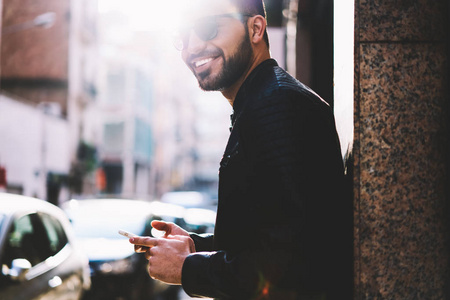 在城市街道上通过蜂窝站在社交网络上的欢快的男性的形象的图像的快乐的博客图片, 微笑的家伙满意4g 连接到互联网上的智能手机在线聊