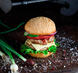 新鲜自制的汉堡, 生菜, 奶酪, 洋葱和西红柿在一个简陋的木板上