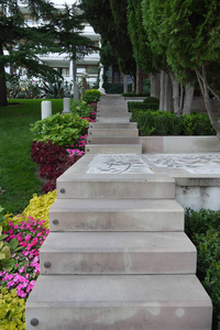 由大的混凝土板制成的楼梯, 通过花坛和草坪与花园, 导致房子