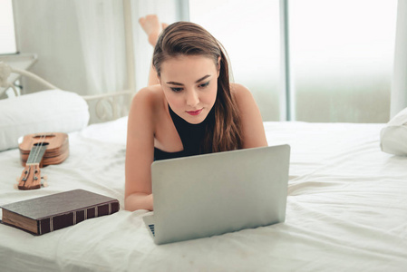 白种女人在舒适的卧室放松, 在家里使用笔记本电脑. 休闲活动概念