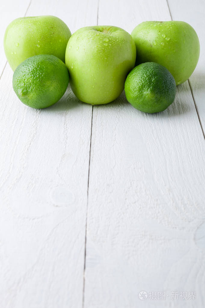 白色的木制背景上的绿色水果。苹果 石灰。排毒。健康的食物