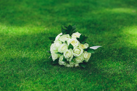 新娘的婚礼花束从白色玫瑰在绿色的草