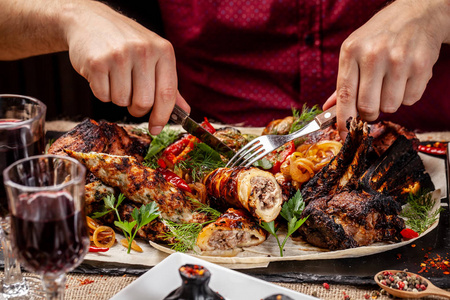 个男人手里拿着一把小刀和一把叉子, 在格鲁吉亚餐馆的烧烤架上烤着肉