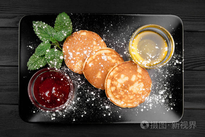 早餐燕麦煎饼与果酱和蜂蜜的黑色木质背景