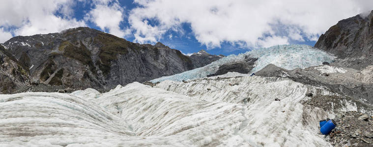 在前景中包含紧急救援物资的蓝鼓的 Franz 约瑟夫冰川全景图