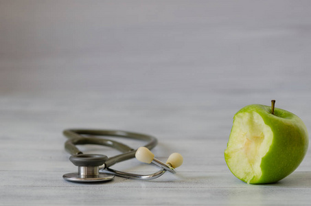 新鲜绿色苹果与叮咬隔绝和听诊器在白色木质背景