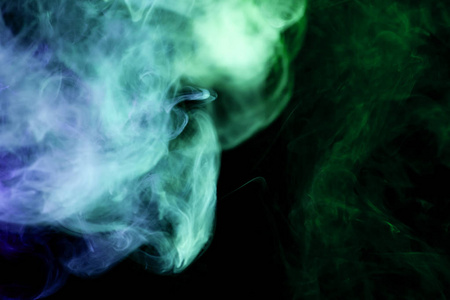 蓝色和绿色烟雾在黑色孤立的背景。背景从 vape 的烟雾