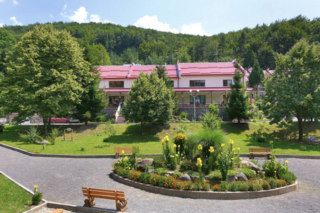 圆形房子有一个红色的屋顶和一个公园, 在它面前的圆形花坛的平房房子