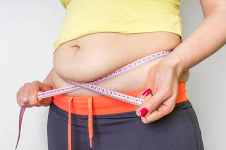 胖女人用胶带测量腹部脂肪