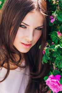 美丽的年轻女子，长卷发玫瑰花园里附近摆姿势。香水广告的概念