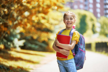 手里拿着本书所小学的学生。附近建筑户外背包的女孩。开始的经验教训。秋天的第一天