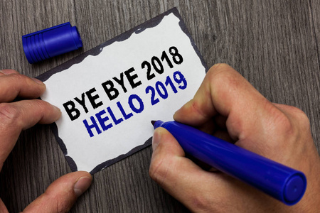 手写文字再见2018你好2019。概念意义开始新年励志消息2018是在灰色木甲板手举行黑色标记写黑色衬里粘纸条
