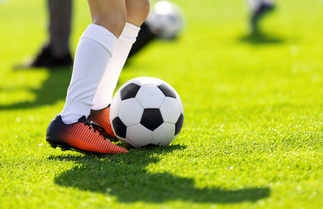 一个年轻人在户外踢足球.年轻的足球运动员在草地上训练.