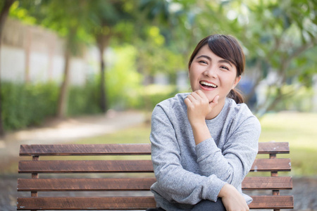 幸福的女人坐在公园的板凳上