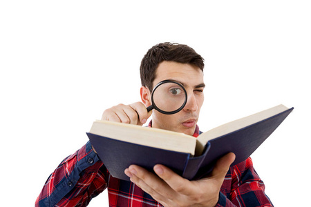 好奇的年轻学生男人拿着本书用放大镜