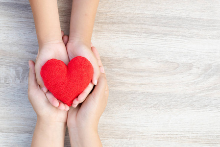 成人和儿童手拿着手工的红色心脏在木背景照片