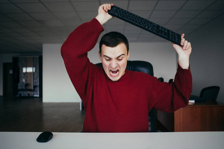 在办公室的情况.一个年轻人在他手中的键盘照片