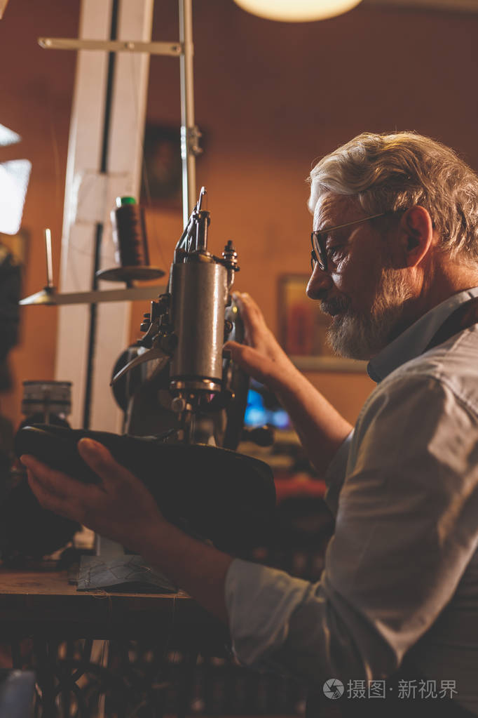 一个穿着围裙的老鞋匠在工作