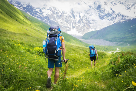 徒步旅行的游客们沿着高地上的绿色山丘漫步。爬山。一群游客徒步上山。休闲。假日在山。冒险在高加索