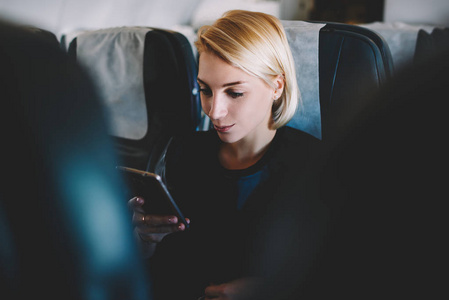 美丽的邦德女性乘客检查电子邮件在线与无线互联网连接在商务旅行中坐头等舱舒适座椅