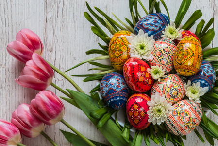 复活节彩蛋与轻木背景粉红色郁金香的复活节背景。插花形式的巢