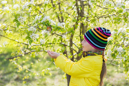 可爱的小女孩正在捉一只蝴蝶在公园里.在花朵盛开的苹果树.