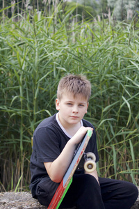 一个有滑板的少年。握着一只手里的滑板