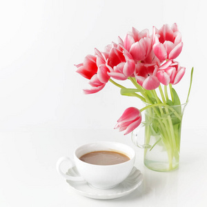 郁金香在白色桌子上的玻璃和咖啡杯子