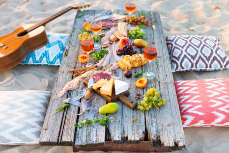 在日落的海滩上波西米亚风格的野餐。浪漫晚餐, 朋友聚会, 夏日, 食物和饮料概念