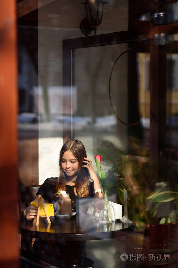 女孩喝咖啡和手表视频在手机上