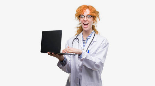 年轻红头发的医生拿着电脑笔记本电脑吓得大吃一惊, 惊恐的表情, 害怕和激动