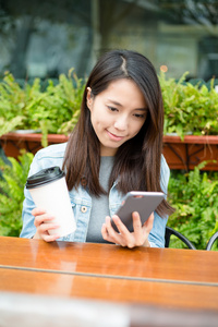 女人看着手机在户外咖啡厅