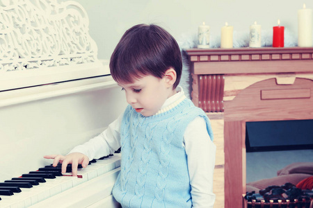 一个小男孩正坐在钢琴旁