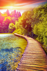 在克罗地亚普利特维切国家公园日落时穿过湖泊的木制小径砌体