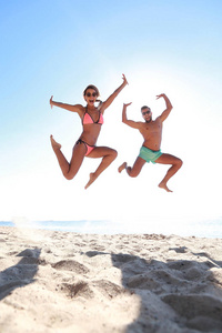 幸福的情侣在海滩上跳跃