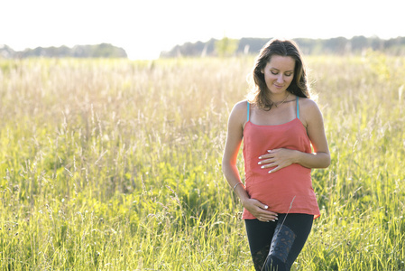 幸福的家庭,夫妇在城市公园, 夏季, 绿草和树木怀孕的女人坐在草地上