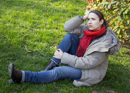 女人坐在红色的围巾在草地上