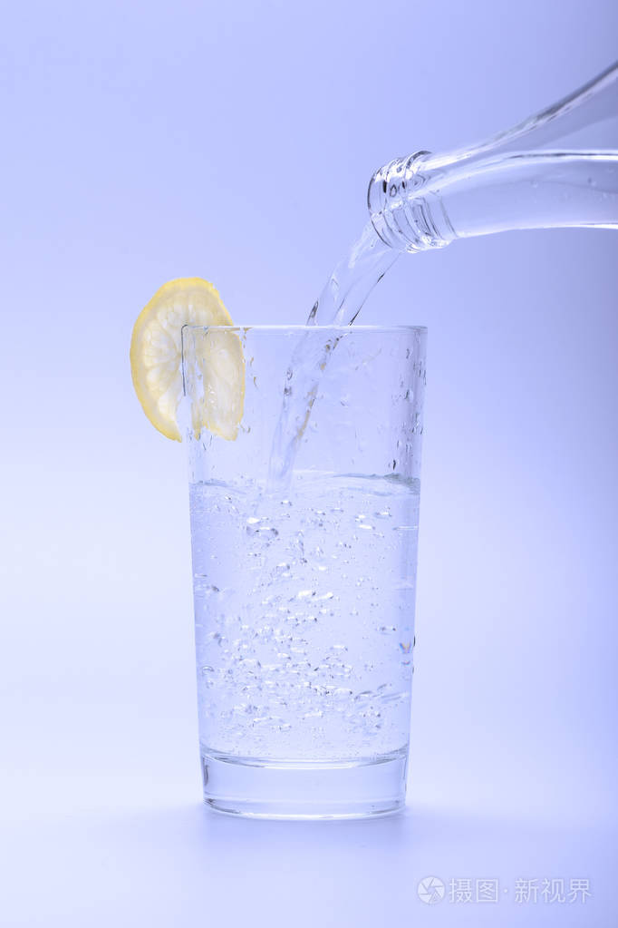 冰冷的淡水从瓶子里倒入一杯柠檬水中