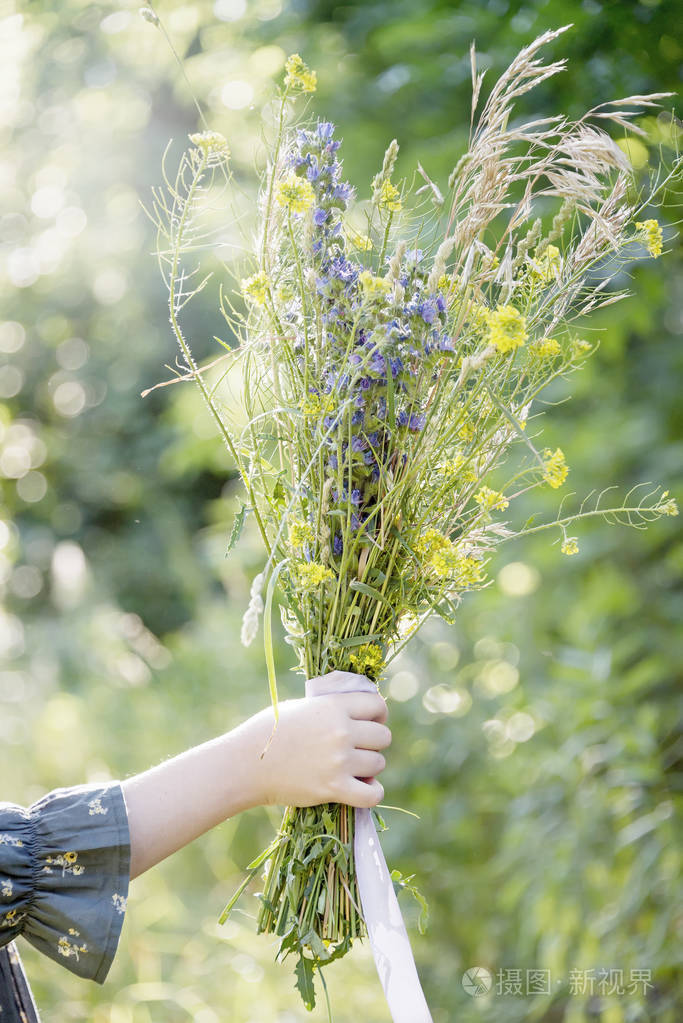一束野花在一个小女孩的手中, 而在树林中漫步