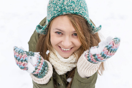 一个年轻漂亮的金发女郎, 长着一头金色的长发, 享受着第一场雪。绿色的夹克, 绿色的帽子和手套。顶部视图。复制空间