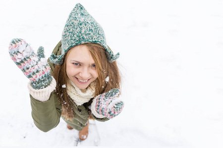 一个年轻漂亮的金发女郎, 长着一头金色的长发, 享受着第一场雪。绿色的夹克, 绿色的帽子和手套。顶部视图。复制空间