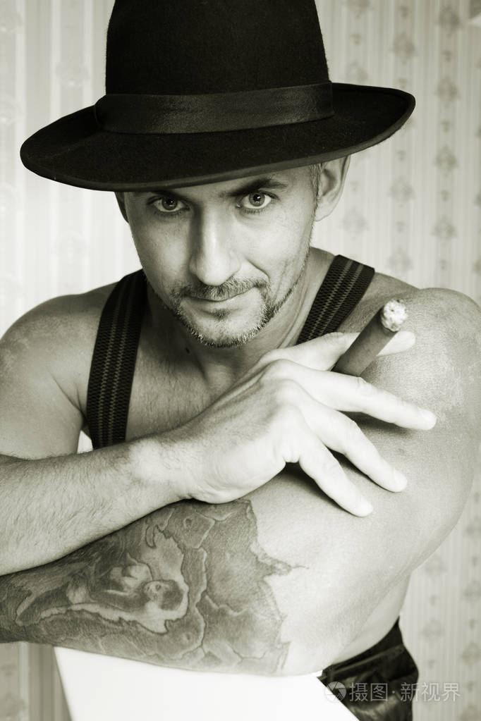 在一顶毡帽在照片中的黑色和白色的手中叼着雪茄的男子气概