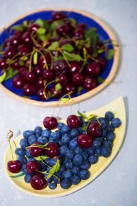 在桌上的盘子里多汁成熟的蓝莓和樱桃。夏天, 浆果, 美味的食物, 健康的概念