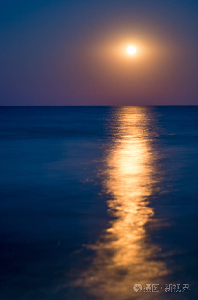 月亮在夜空中蔚蓝的天空海的地平线波浪反射的光垂直组合