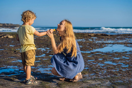 母亲和儿子沿着宇宙巴厘岛海滩漫步。肖像旅行游客母亲与孩子。积极的人类情绪, 积极的生活方式。海边快乐的小家庭